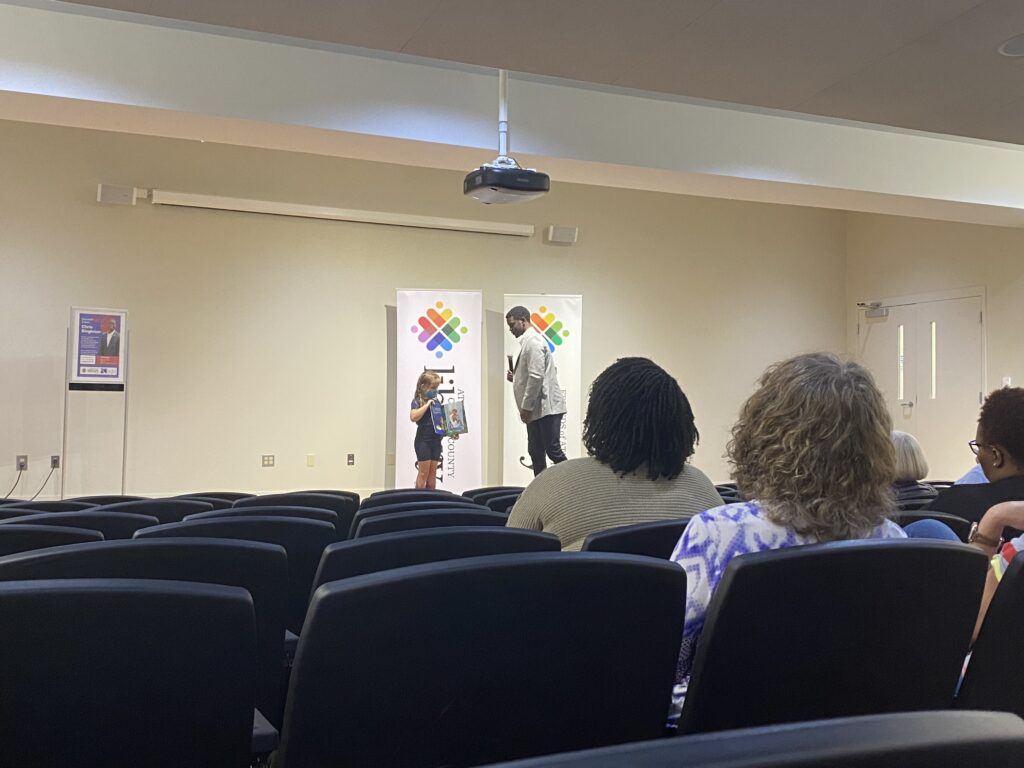 Chris Singleton reading his new book with the help of a young girl. 